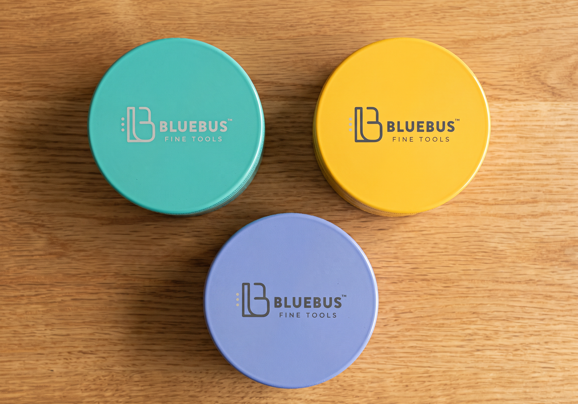 Three GC ceramic herb grinders in teal, yellow and lavender arranged on an oak table